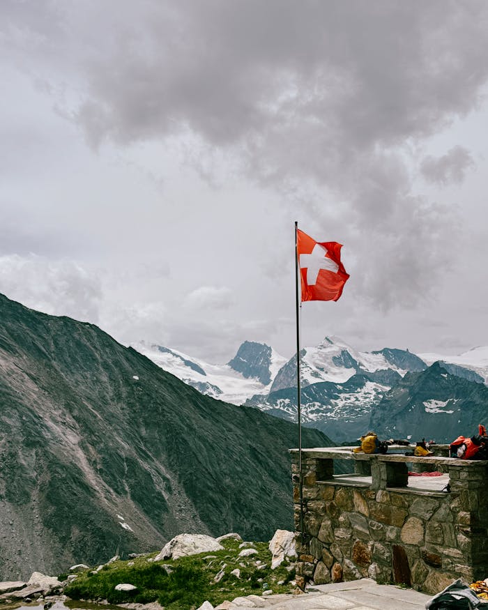 Stunning panoramic view of the Swiss Alps with a prominent Swiss flag in the foreground.