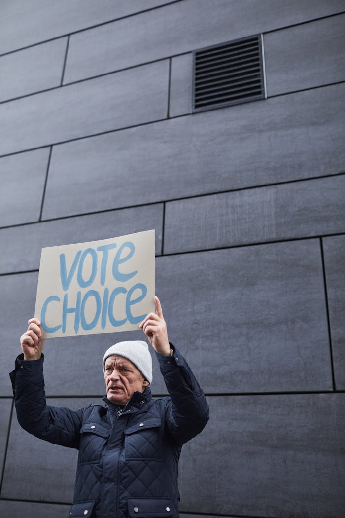 Elderly man holding a 'Vote Choice' sign during an outdoor protest, showcasing activism.