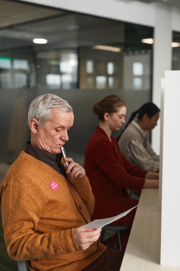 Senior man reviewing a ballot at an indoor polling station on voting day.